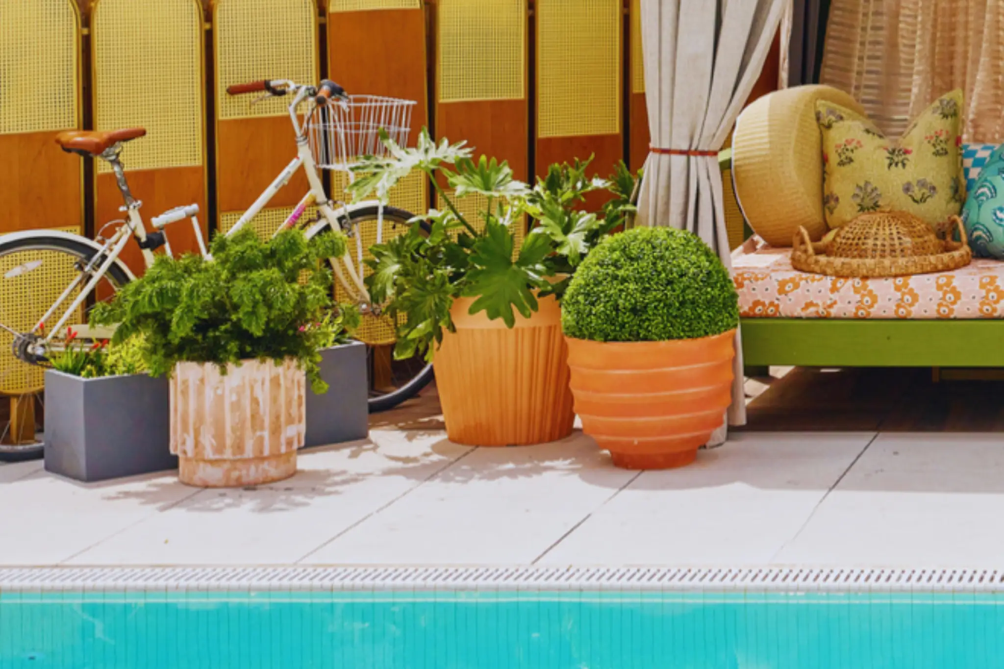 A quirky white vase shaped like a buttocks, filled with apple slices, sprigs of rosemary, and a stick of cinnamon on a wooden table.